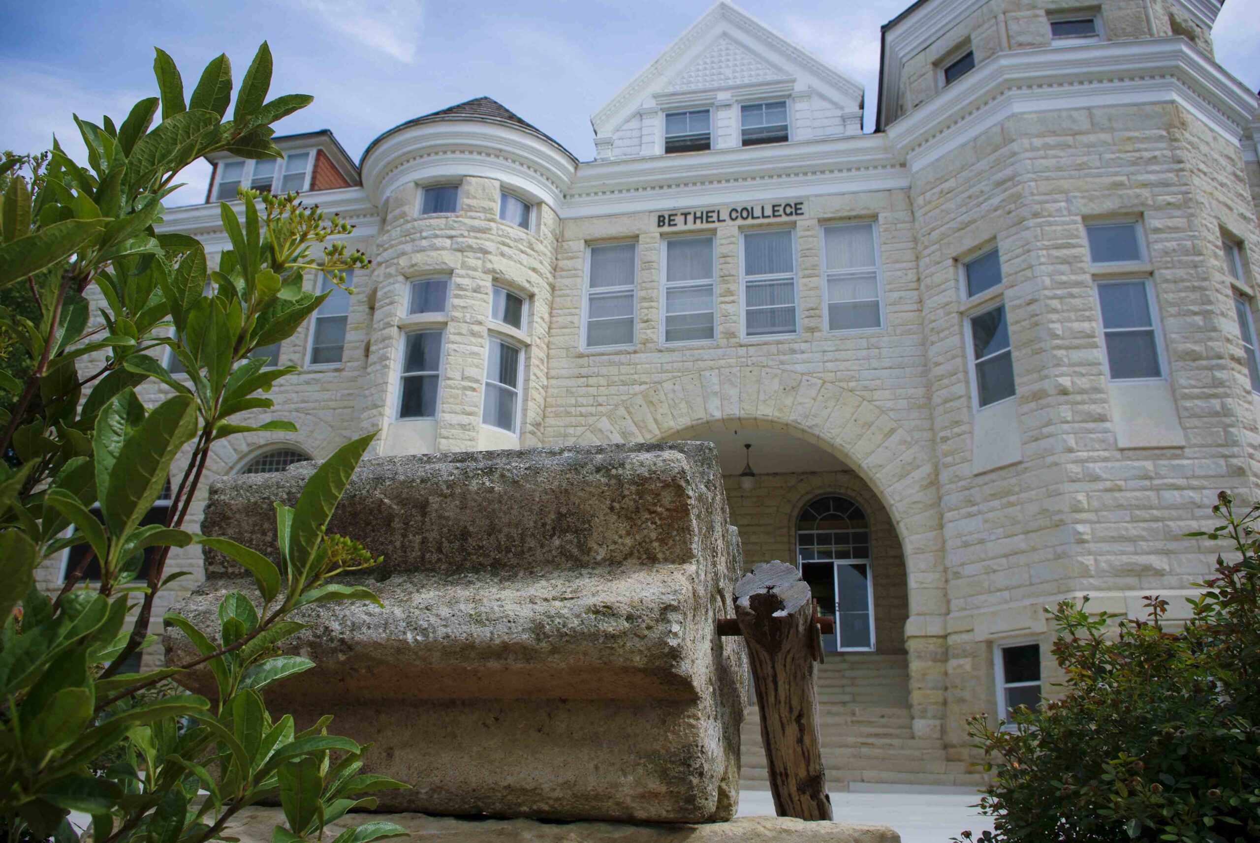 Close-up of threshing stone in front of Ad Building, with Ad Building in the background