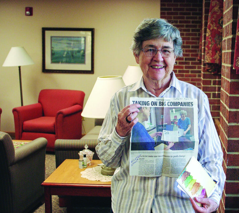 Sister Barbara McCracken holding a newspaper with a story about the sisters' activist investment strategies