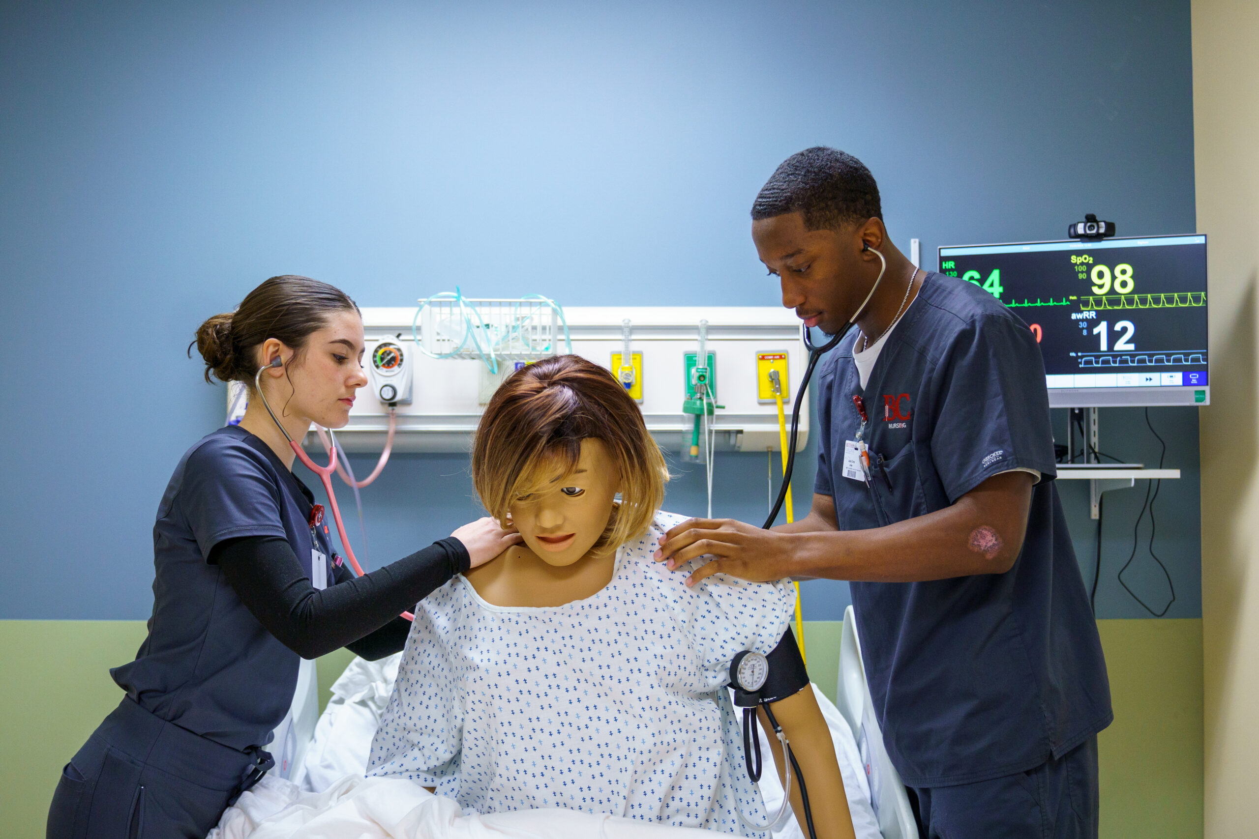 Two nursing students care for a "patient" in the sim lab.