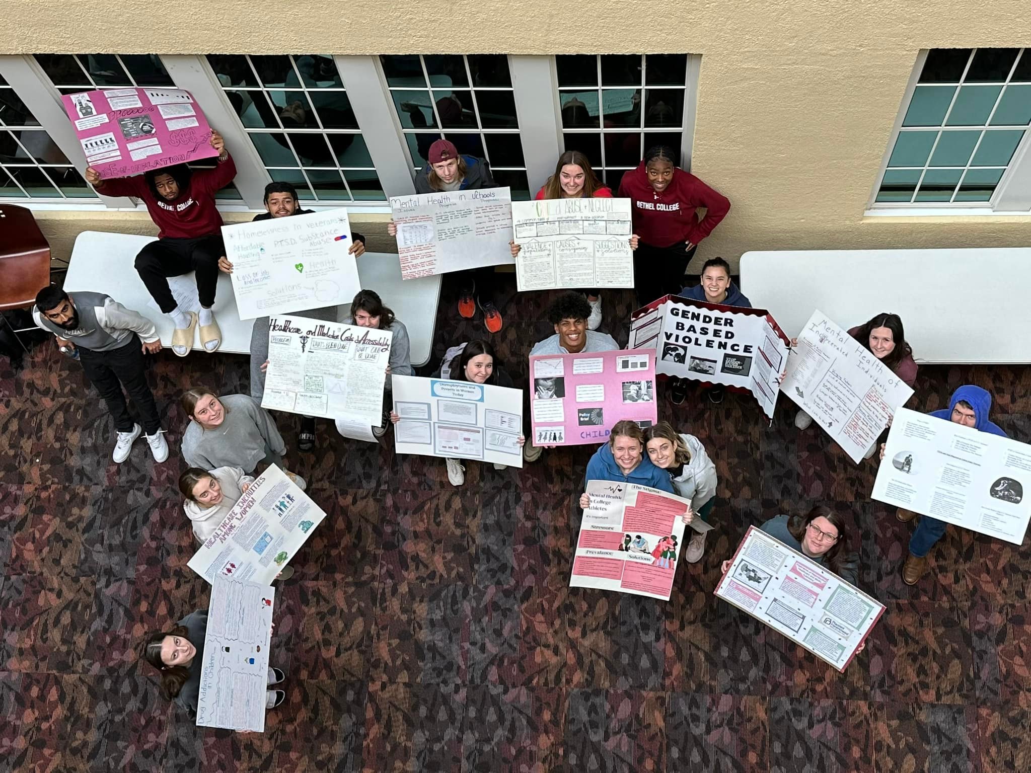 A group of students holding signs looking up at the camera.