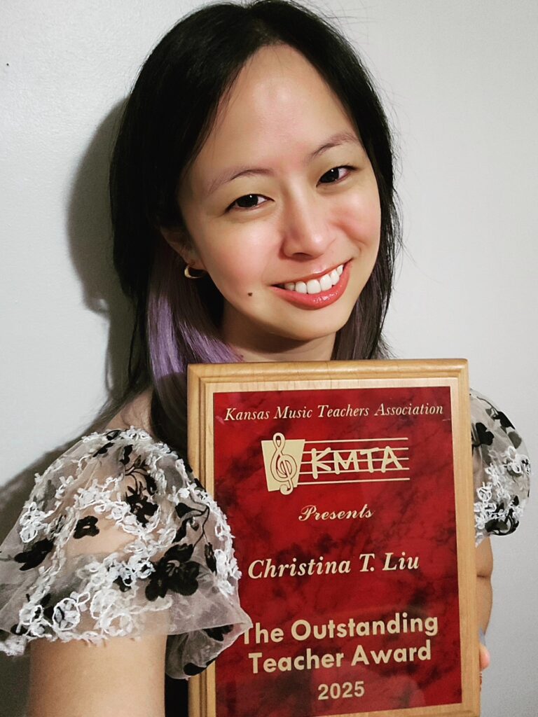 Christina Liu holds her award, a red plaque with gold lettering