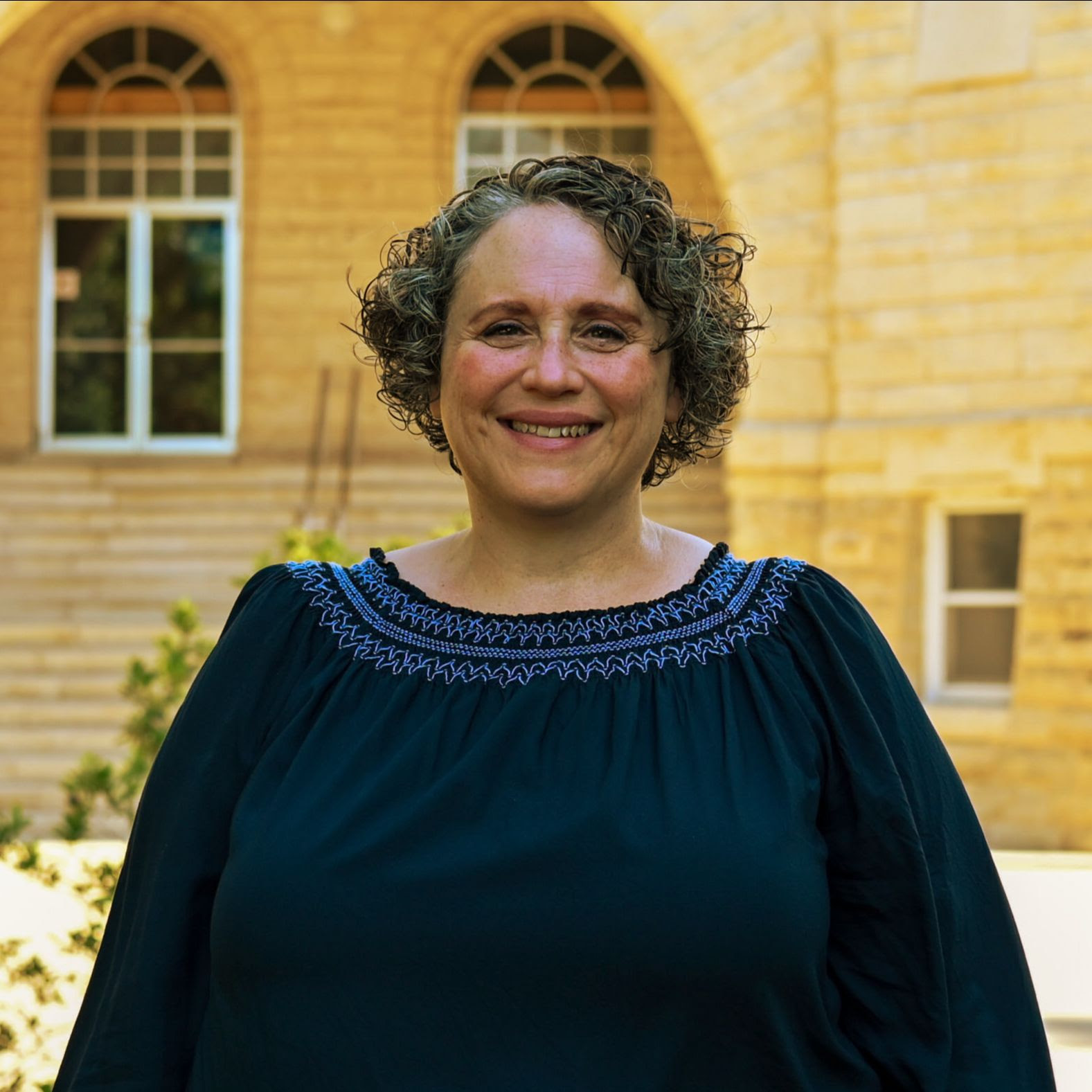 Holly Swartzendruber, headshot, in front of the Ad Building