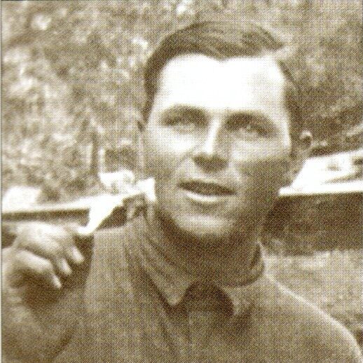 Photo from the early 20th century, sepia-toned, of a young man eating a meal outdoors