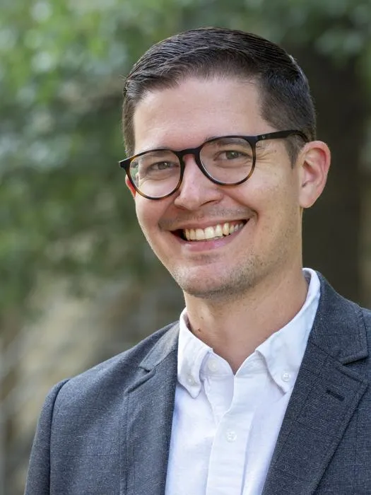 Head shot of Will Wiebe Friesen outdoors, in dark-colored suit coat and white collared shirt